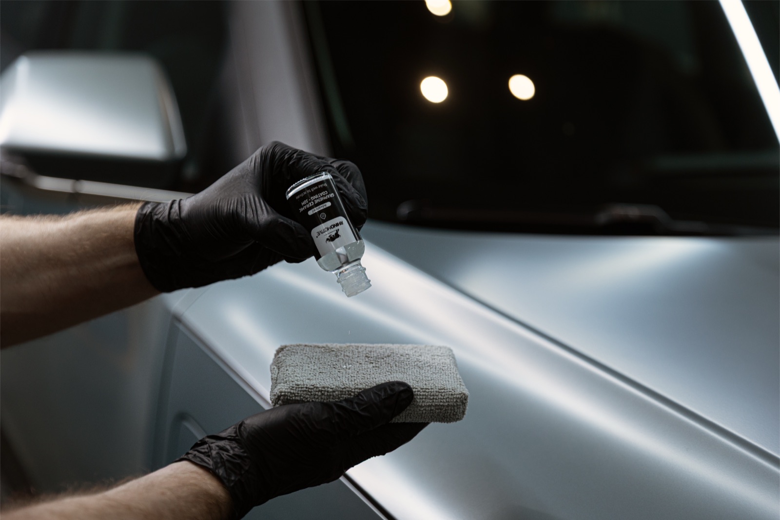 Technician applying ceramic coating to a car exterior at Auto Millennium Dubai